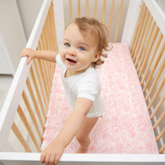 Crib sheet on standard mattress by aden + anais, demonstrating secure elastic fit