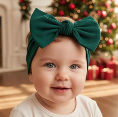 BABYGIZ dark green bow headband worn during play, keeping hair away from face.