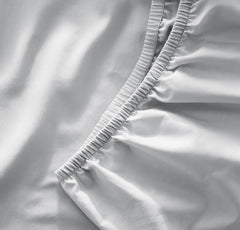 Boll & Branch signature crib sheet sky close-up showing secure elastic for snug fit.