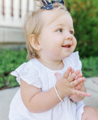 Cherished Moments sterling silver cross baby bracelet shown from the side, highlighting safe wear for infants.