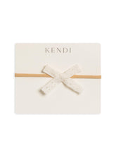 Colored Organics baby bow coconut linen front view showcases soft organic cotton comfort.