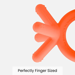 Comotomo teether orange on lap during playtime for on-the-go soothing.