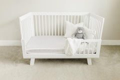 Two white satin crib sheets with light pink hearts for nursery.
