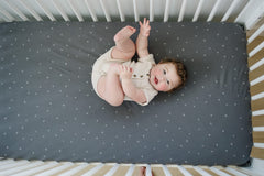 Ecolino on-mattress display showing universal elastic hem for secure crib fit.