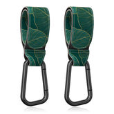Gukeniu stroller hook close-up showing the green-leaf strap for hands-free bag handling.