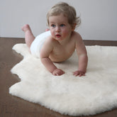 HUAHOO premium baby sheepskin rug ivory white on a nursery crib for cozy comfort.