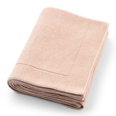 Huxie knitted baby blanket in blush folded for cozy warmth and portability.