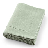 Huxie knitted organic baby blanket in Roman Green folded for warm, cozy nursery vibes.