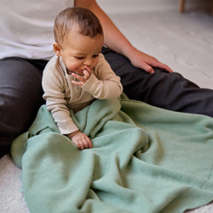 Huxie knitted organic baby blanket on stroller illustrates versatile use during outings.