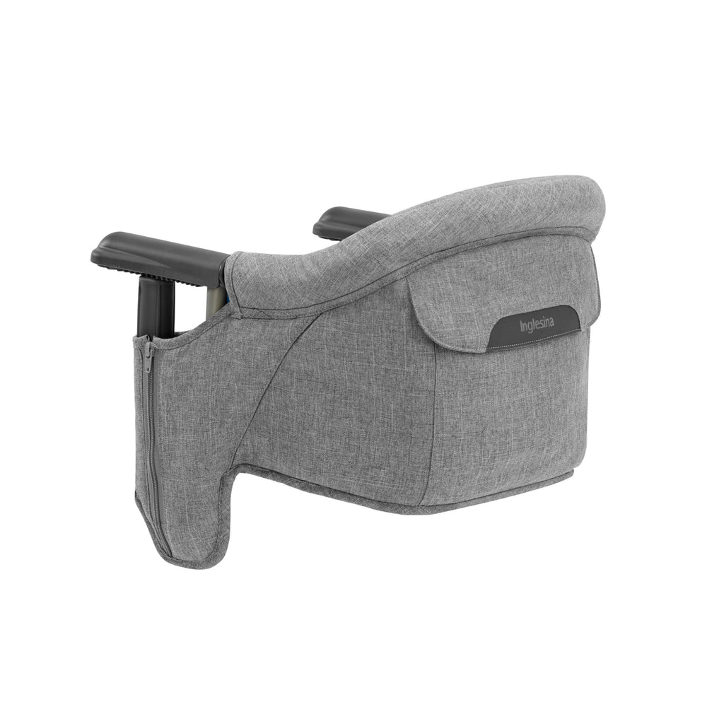 Inglesina Fast Table Chair stone gray melange folded beside travel bag for easy on-the-go meals