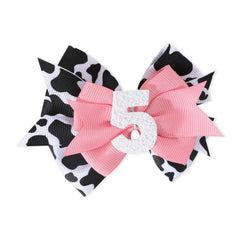 Jissoo cow print bow headband in pink, lightweight accessory for baby’s birthday outfit.