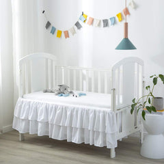 JSD white ruffled crib skirt with double-layer design adds soft texture to nursery.