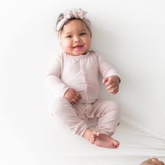 KYTE BABY bow on baby head, adjustable fit for comfy wear.