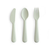 Mushie dinnerware cutlery set sage fork in hand supports easy self-feeding.