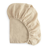 Mushie Extra Soft Muslin Crib Sheet Fog folded for a cozy, ready-to-use look.