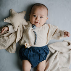 Mushie baby blue muslin sheet on standard crib mattress highlights deep pockets.