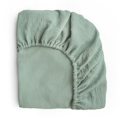 Mushie extra soft muslin crib sheet flatlay in Roman Green highlighting breathable warmth.