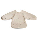 Mushie long sleeve bib Rainbows worn by baby showing full coverage during meals.