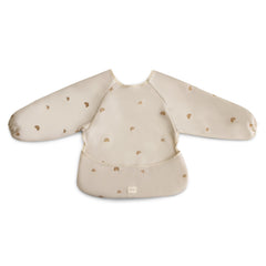 Mushie long sleeve bib Rainbows worn by baby showing full coverage during meals.