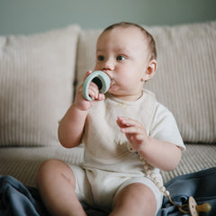 mushie muslin bib worn by baby during teething drool