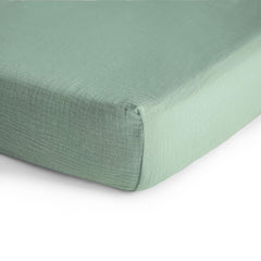 Mushie muslin crib sheet on mattress close-up in Roman Green with elastic edge.
