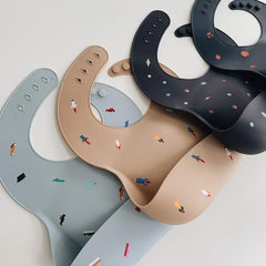 Mushie rocket ship bib neck-fastener detail demonstrates adjustable fit during feeding