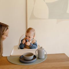 Mushie rocket ship bib pocket-full during snack time demonstrates spill control