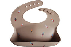Mushie rocket ship bib worn on baby illustrates flexible, comfy silicone