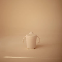Mushie Trainer Sippy Cup Ivory handles grip for easy self-feeding.