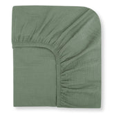 Nora's Nursery muslin crib sheets in sage—soft close-up highlighting breathable organic cotton texture.