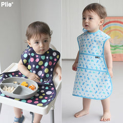 Plie bib on toddler for self-feeding in a high chair.