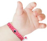 Red baby bracelet with evil eye closeup highlighting the protective charm