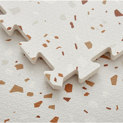 Simple Kid Co baby crawls on the neutral terrazzo mat offering cushioned, safe play.