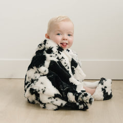 Trend Lab cow print plush back shows warm white side for cozy naps.