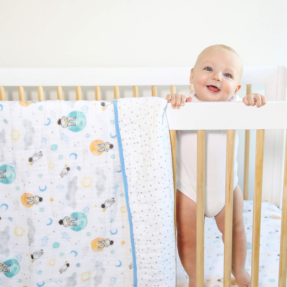 aden + anaïs Essentials Dream Blanket under a baby resting with space explorers print for soft warmth.