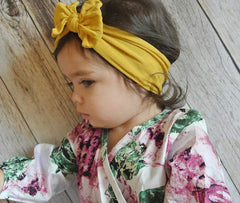 AKOAK yellow headband on baby demonstrates stretchy, snug fit for all-day wear.