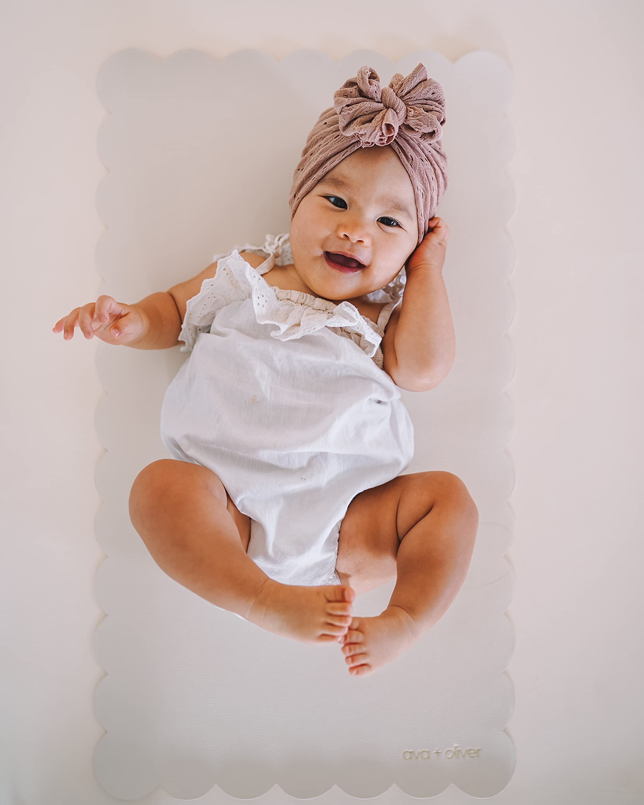 AVA + OLIVER vegan leather baby changing mat, cream scallop folded for compact travel and storage.