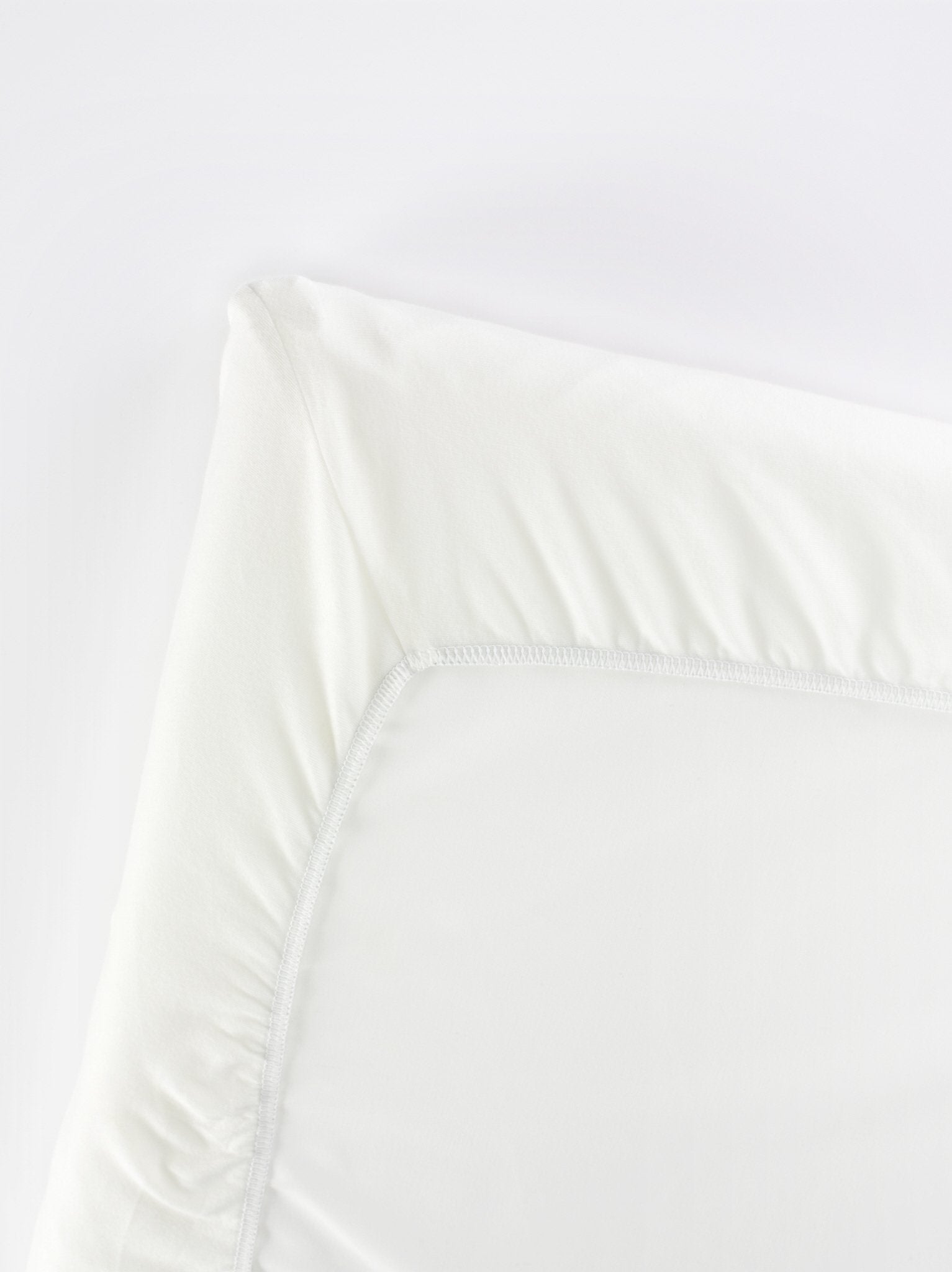 BabyBjörn Travel Crib Light fitted sheet folded, showing soft organic cotton and compact storage.