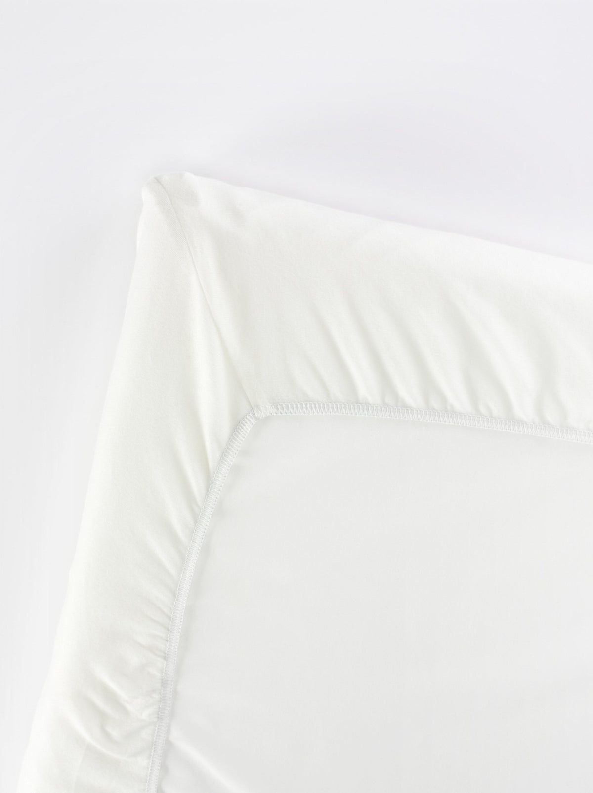 BabyBjörn Travel Crib Light fitted sheet folded, showing soft organic cotton and compact storage.