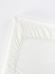 BabyBjörn Travel Crib Light fitted sheet folded, showing soft organic cotton and compact storage.