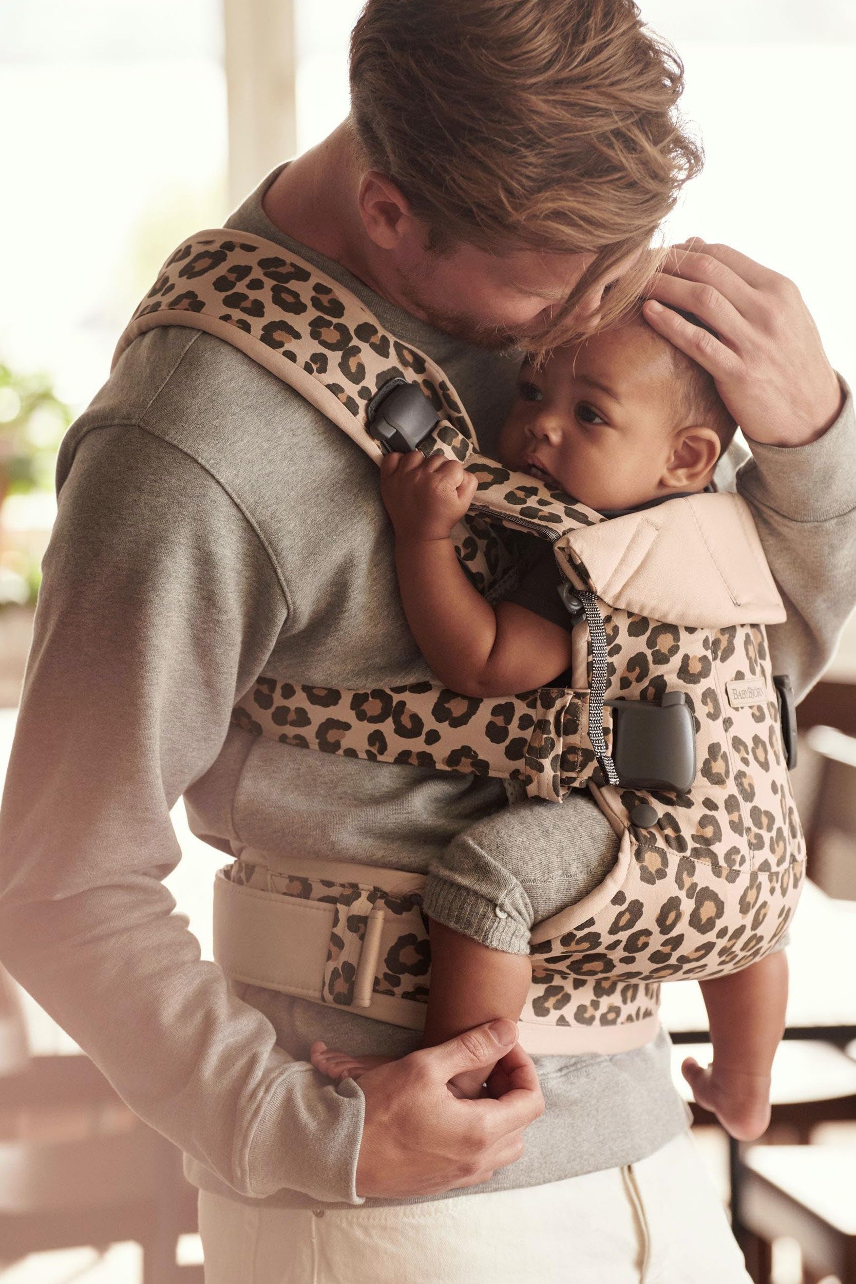 BabyBjörn Baby Carrier One in cotton beige/leopard, side-worn view supports hands-free tasks.