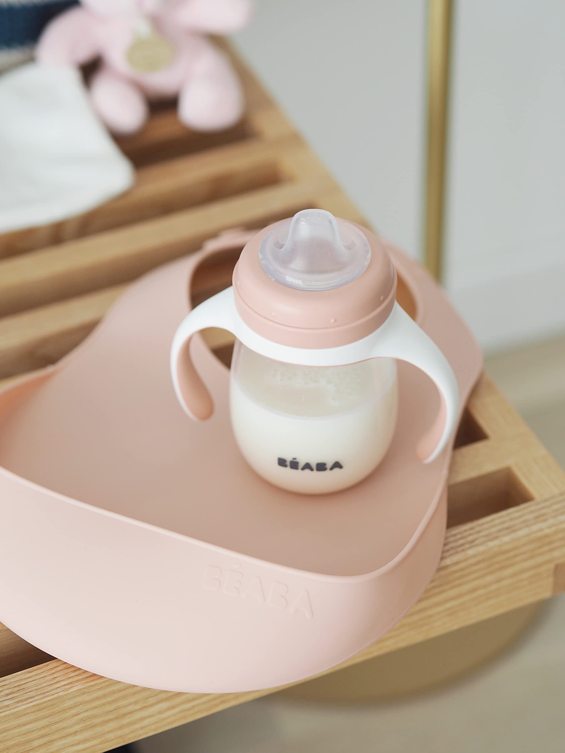 Beaba Rose bib shows food catcher in action, reducing floor spills during mealtimes.