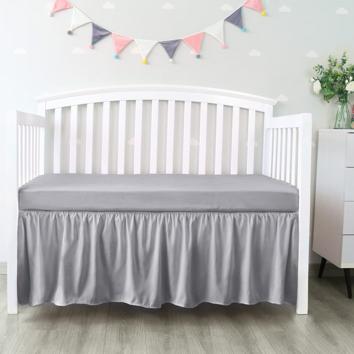 Biloban crib skirt grey front view showing four-sided pleated ruffle for tidy nursery