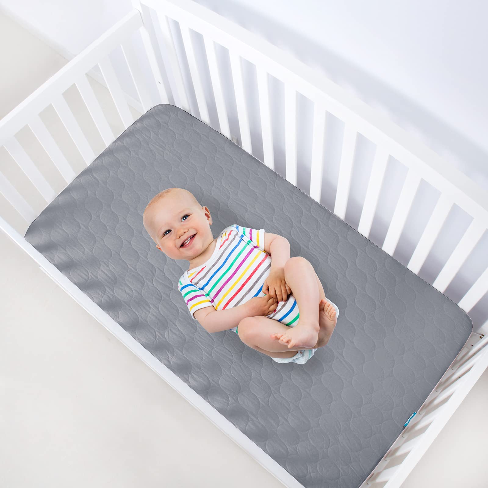 Biloban grey crib pad on mattress demonstrates fitted design for a secure, cozy fit.