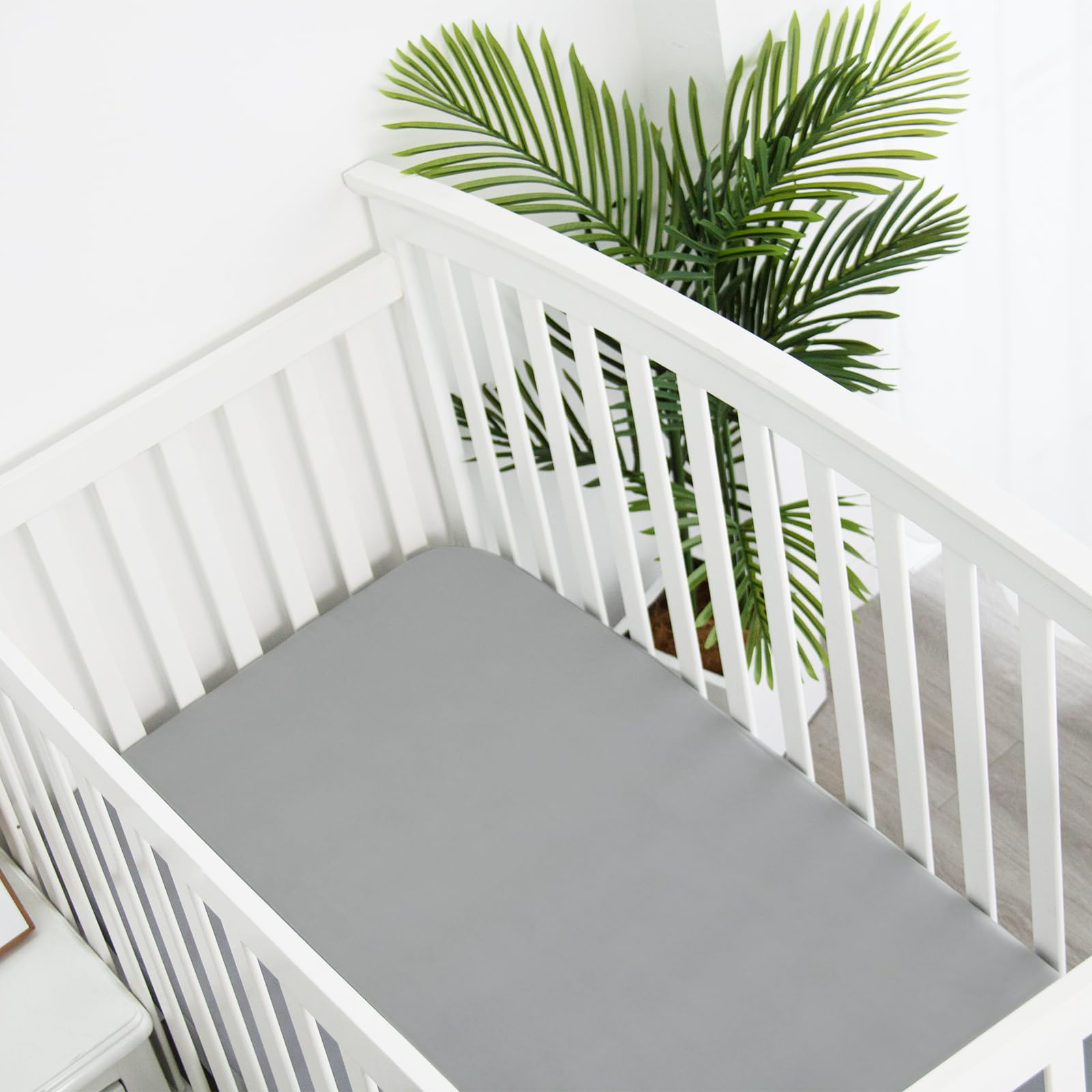 Neutral grey Biloban mini crib sheets in a calm nursery.