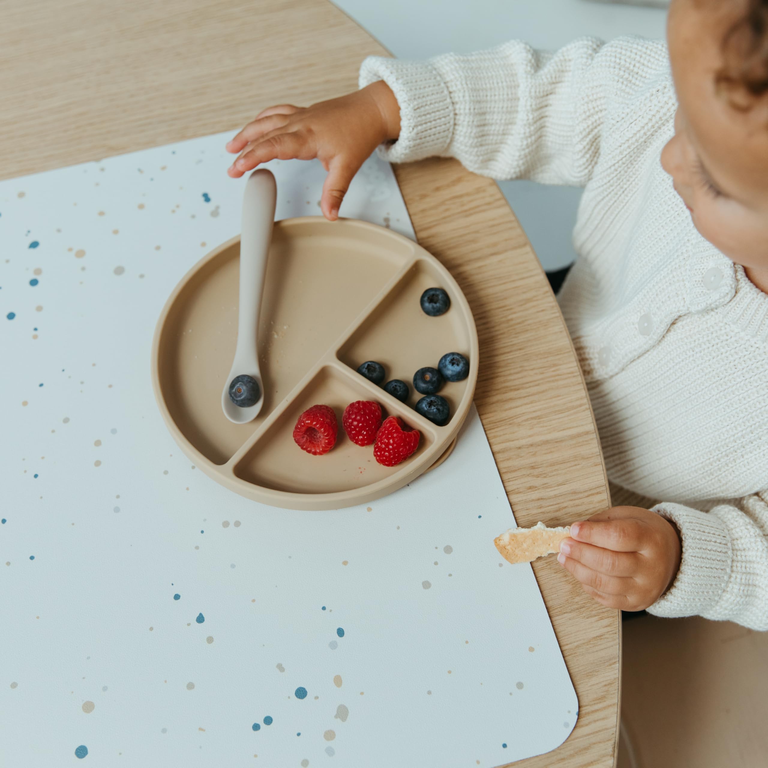 Blooom placemat baby mealtime use demonstrates spill-catching surface for early self-feeding