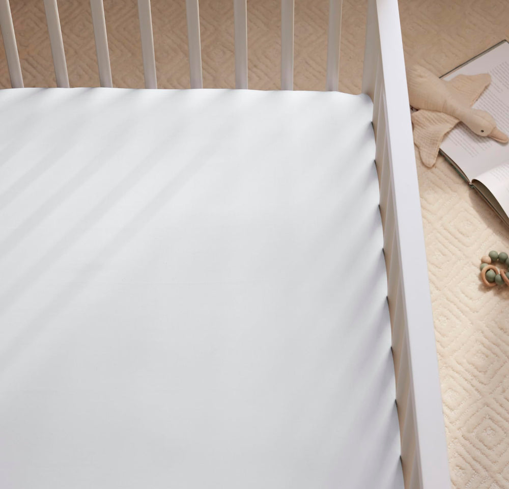 Boll & Branch organic cotton crib sheet in sky, folded neatly to highlight premium material for safe sleep.