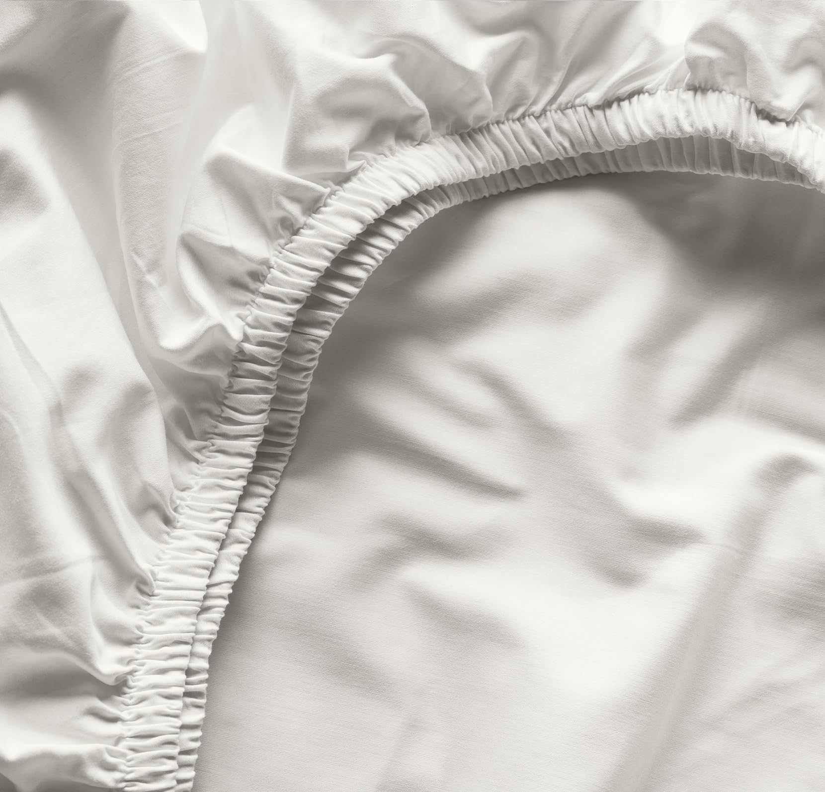 Boll & Branch Signature crib sheet secure-fit elastic band demonstrates snug bedding for standard crib.