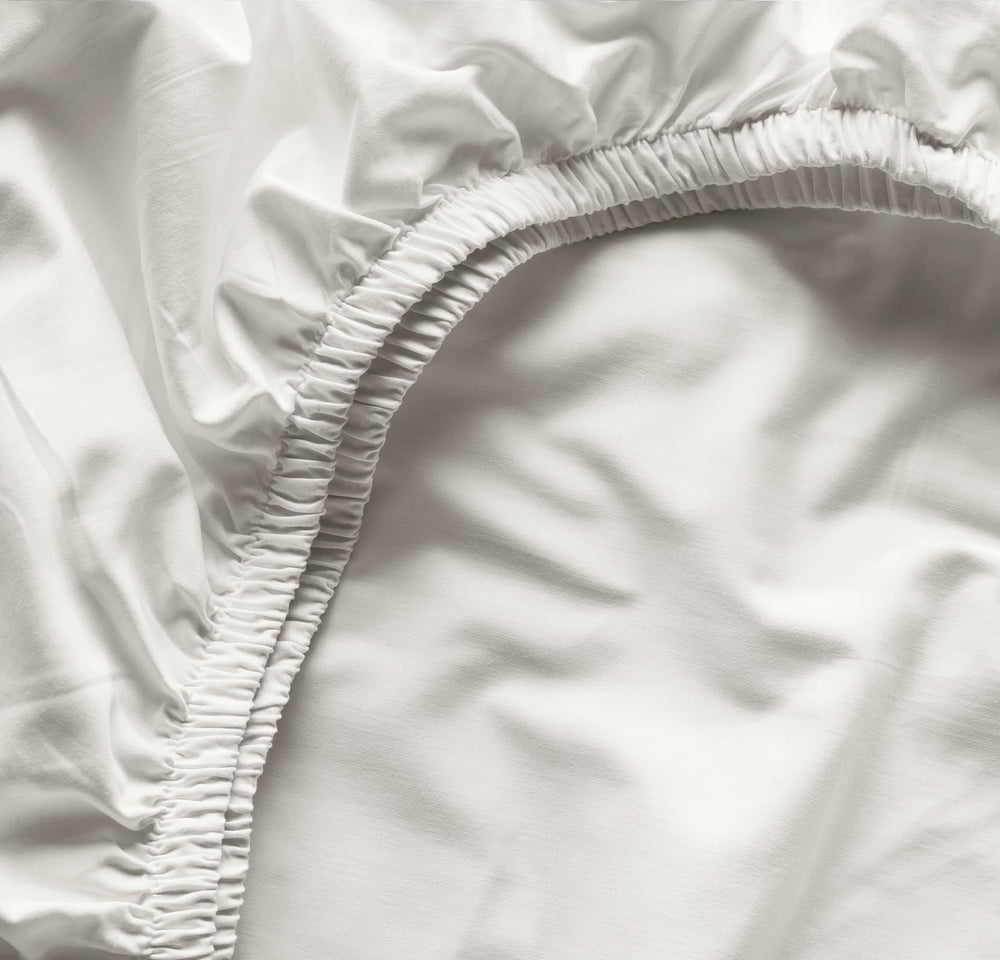 Boll & Branch Signature crib sheet secure-fit elastic band demonstrates snug bedding for standard crib.