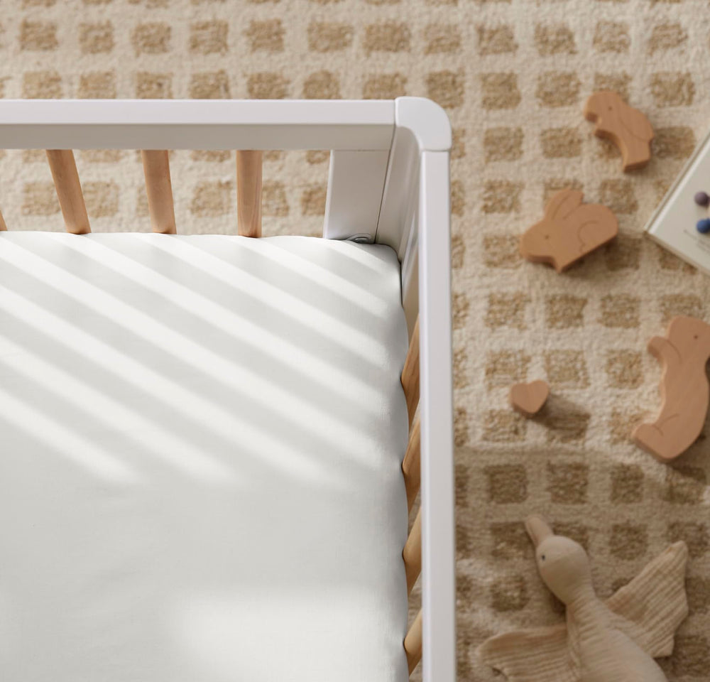 Boll & Branch Signature crib sheet on standard crib mattress illustrates precise fit and durability.